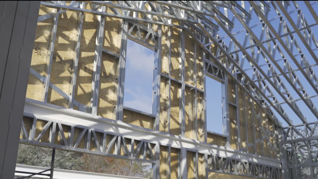 햇빛 아래 건설 현장에서 새로 지은 강철 프레임 하우스의 패닝 샷