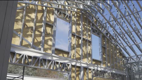 panning shot of new build steel frame house at construction site in sunlight