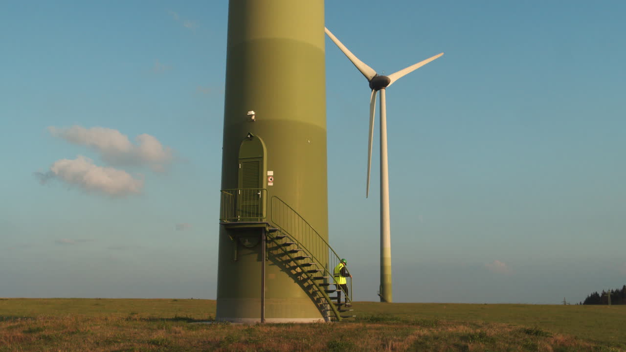 기술자가 풍력 터빈 문에서 계단을 내려갑니다.