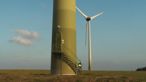 technician walks down the stairs from the wind turbine door