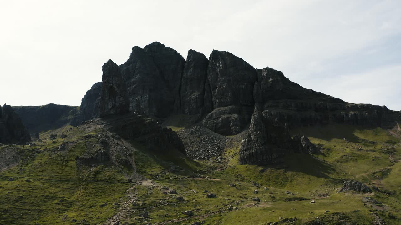 disparo de dron alejándose de la ladera rocosa de storr de escocia para revelar un valle exuberante