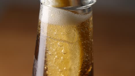 extreme close-up of lemon in glass beer bottle fizzing and bubbling