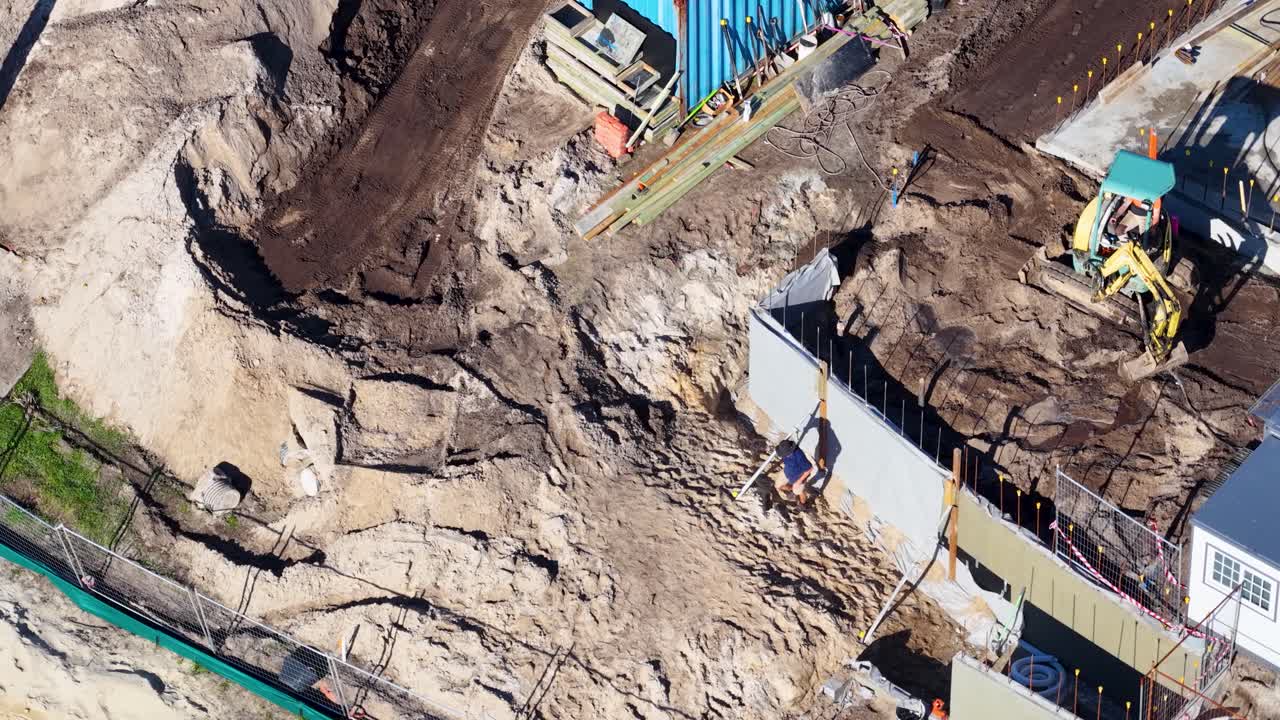 Aerial footage of construction workers and machinery at a building site in Gold Coast, Australia, under bright daylight