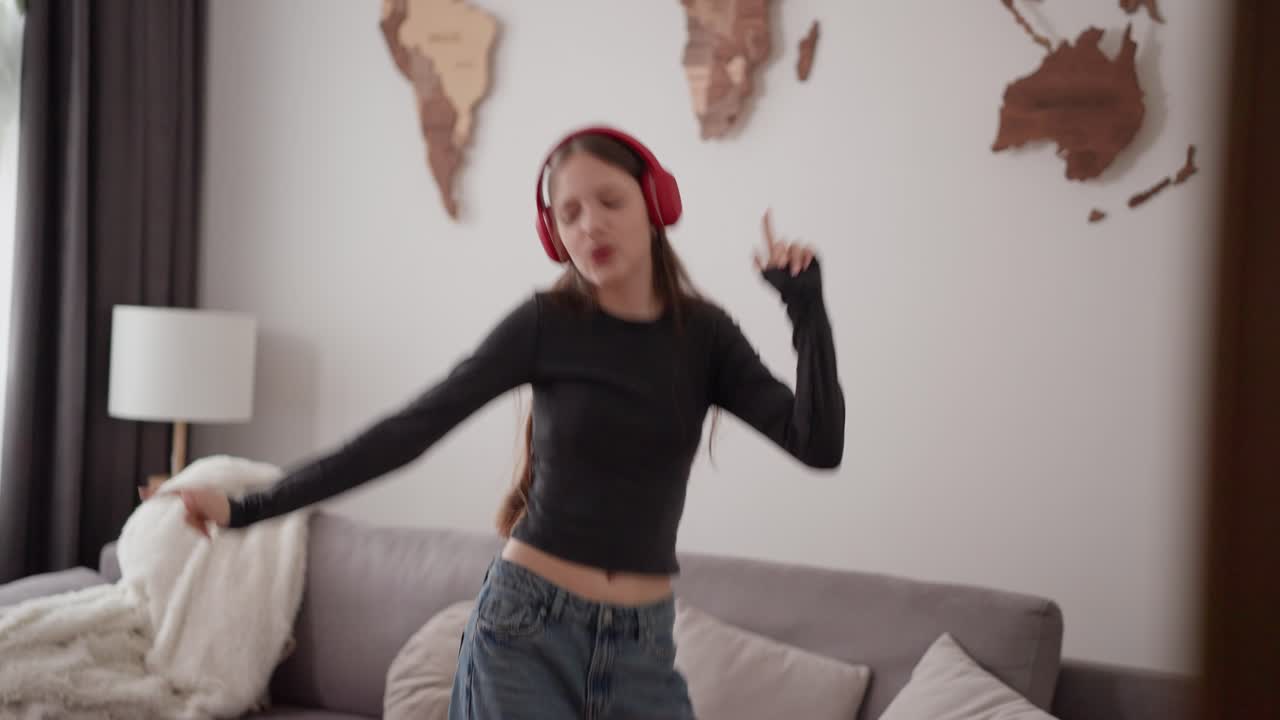 Woman with headphones dancing in living room