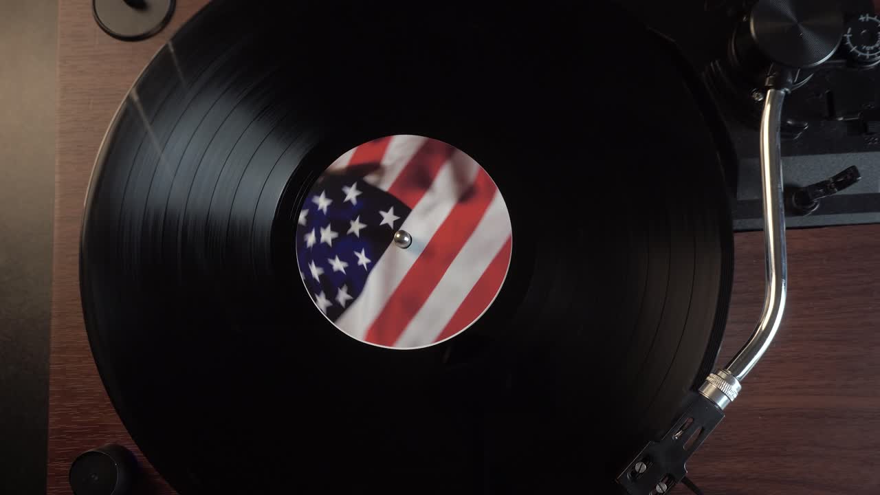 Avvio della riproduzione di un disco in vinile con adesivo della bandiera americana, vista dall'alto