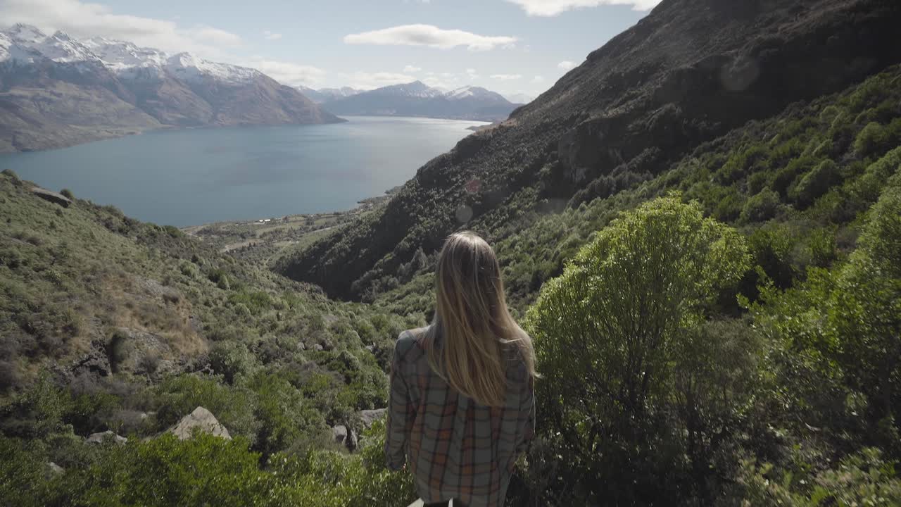 female hiker walking out on scenic platform in beautiful mountain landscape, new zealand