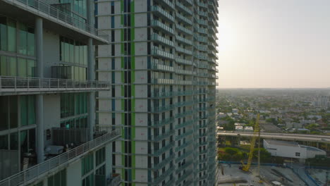 Vuelo-Estrecho-Hacia-Adelante-A-Lo-Largo-De-Modernos-Edificios-De-Apartamentos-De-Gran-Altura.-Revelando-Una-Gran-área-Plana-Con-Vistas-A-Los-Distritos-Urbanos-Residenciales-Contra-El-Sol.-Miami,-Estados-Unidos