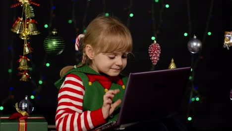 Niña-Vestida-De-Elfo-Navideño-Haciendo-Compras-En-Línea-Usando-Una-Computadora-Portátil,-Navegando-En-Las-Redes-Sociales