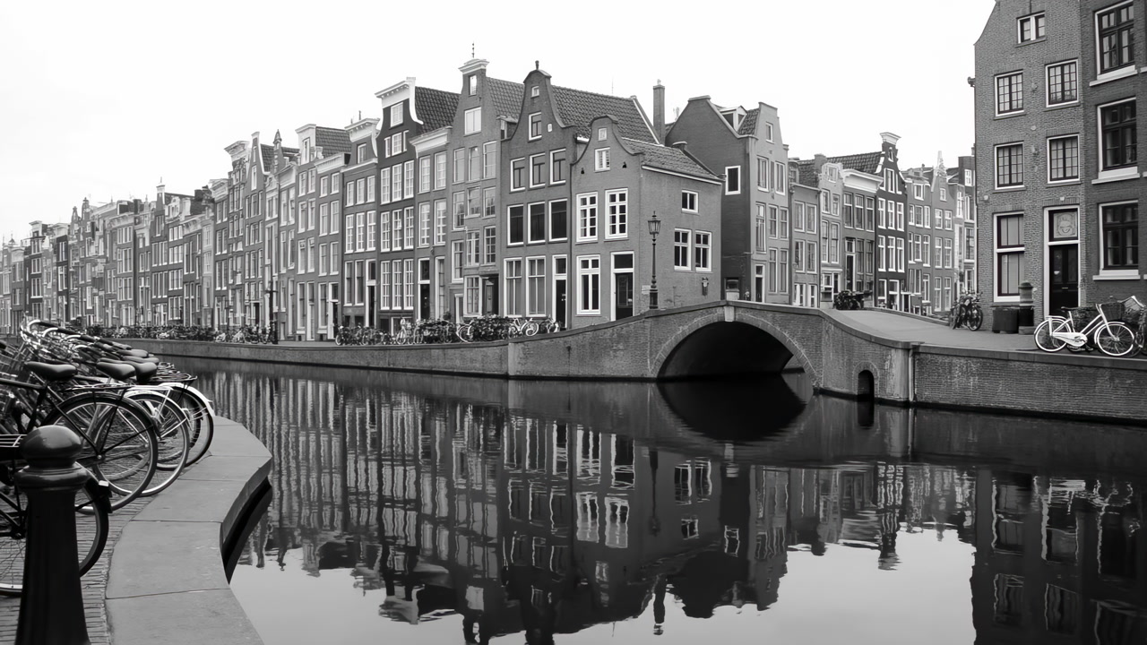 Canal Bridge Bicycles Reflecting Historic Brick Houses, Calm Monochrome Morning With Still Water Mirror