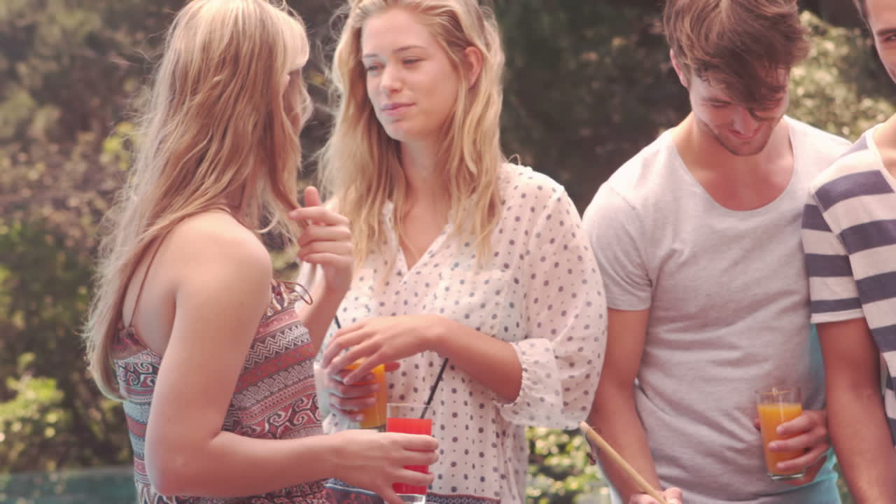 amigos felices haciendo una barbacoa junto a la piscina.