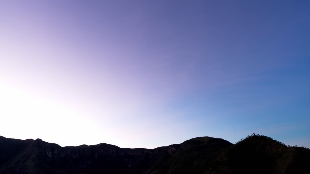 Stunning timelapse of sunrise revealing mountain silhouettes as the sky transitions from black to colorful and clear blue