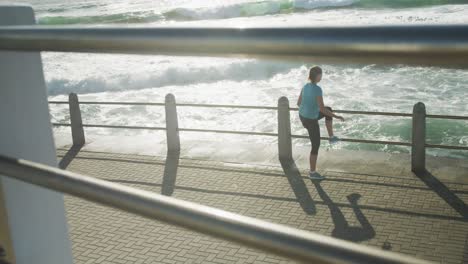 senior woman stretching her legs on a promenade