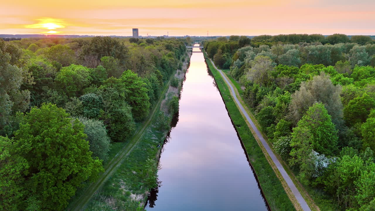 Scenic sunset over a canal. Sunset casts a golden glow over a peaceful canal surrounded by lush greenery in the Netherlands during early evening