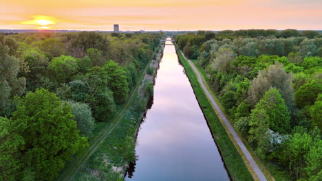 scenic sunset over a canal. sunset casts a golden glow over a peaceful canal surrounded by lush greenery in the netherlands during early evening