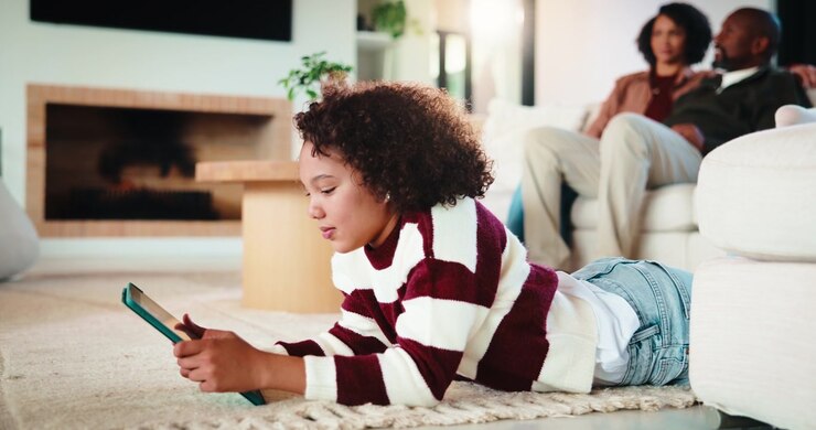 Young Girl Using Tablet While Lying on Living Room Floor