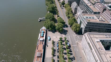 Köln,-Nordrhein-Westfalen,-Deutschland---Langsamer-Luftvogel-Drohnenflug-über-Das-Konrad-Adenauer-Ufer-In-Köln---Promenade-Entlang-Des-Rheins-Mit-Vielen-Bäumen,-Radweg-Und-Vierspuriger-Straße