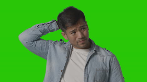 studio shot of casually dressed stressed young man against green screen