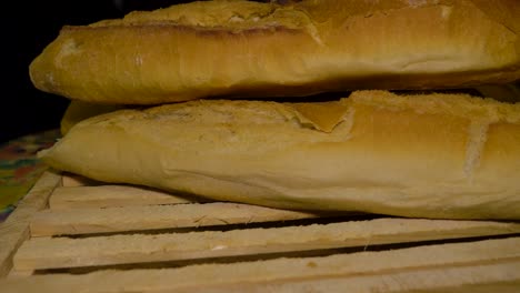 man removes stack of galician bread and adjust placement then puts fresh loaf across board