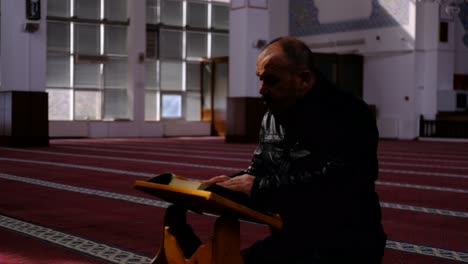 middle age man reads the quran in masjid