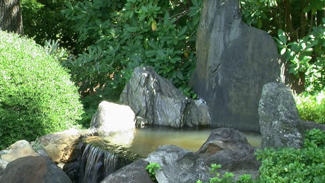 a small ornamental waterfall nestled among garden plants