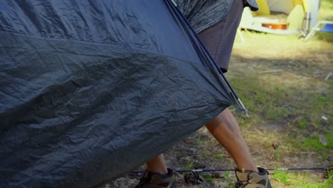 man setting up tent in the forest on a sunny day 4k