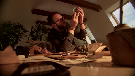 man examining a crystal globe in a study filled with antique objects