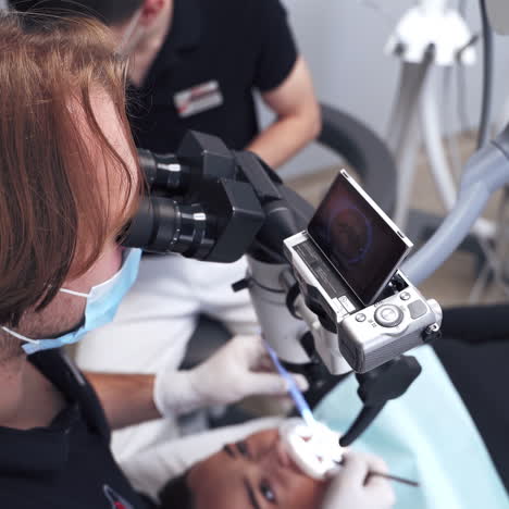professional dentist treats teeth of a young woman. stomatologist examines patient's teeth through the modern microscope. new technologies in medicine.