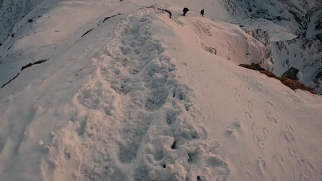 Mountain-Climbers-Hiking-Downhill-the-Snowy-Path-at-Twilight,-First-Person-View