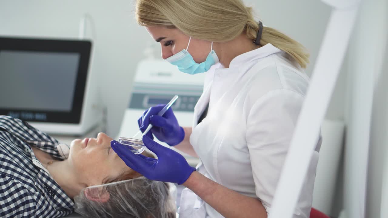 La cosmetologa leviga le rughe con la microcorrente. Procedura strumentale in cosmetologia. Peeling, fonoforesi, massaggio e lifting in una clinica estetica.