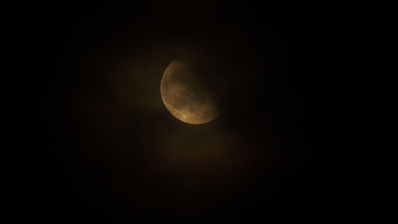 Clouds slowly passing in front of a bright moon at night