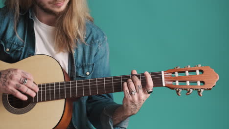 caucasian young man playing guitar on camera.