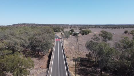 drone volando sobre una carretera de campo y un puente en el interior de australia