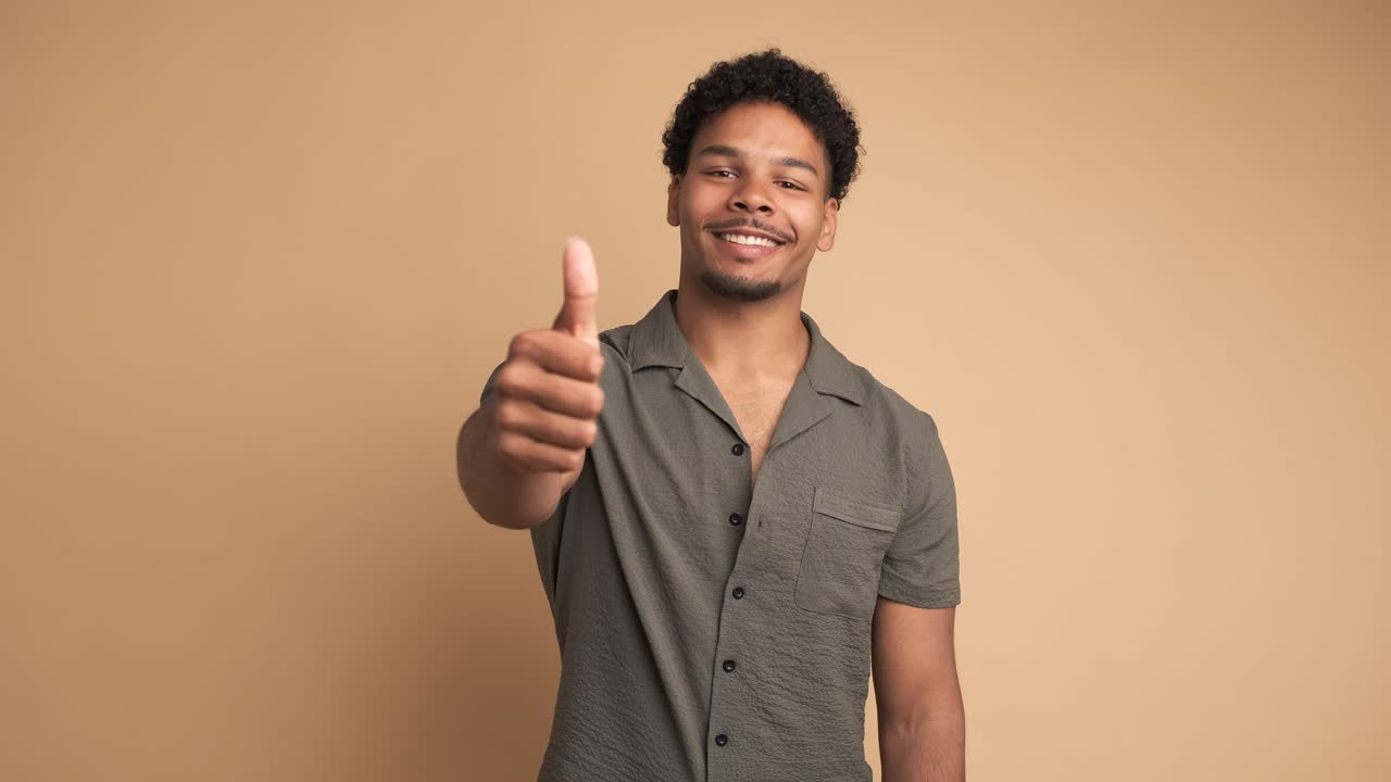 Smiling man making thumbs up gesture and nodding to show approval