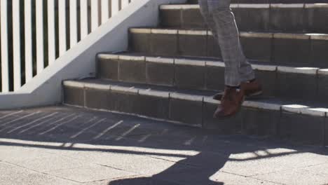 piernas de un hombre afroamericano caminando por las escaleras en la ciudad