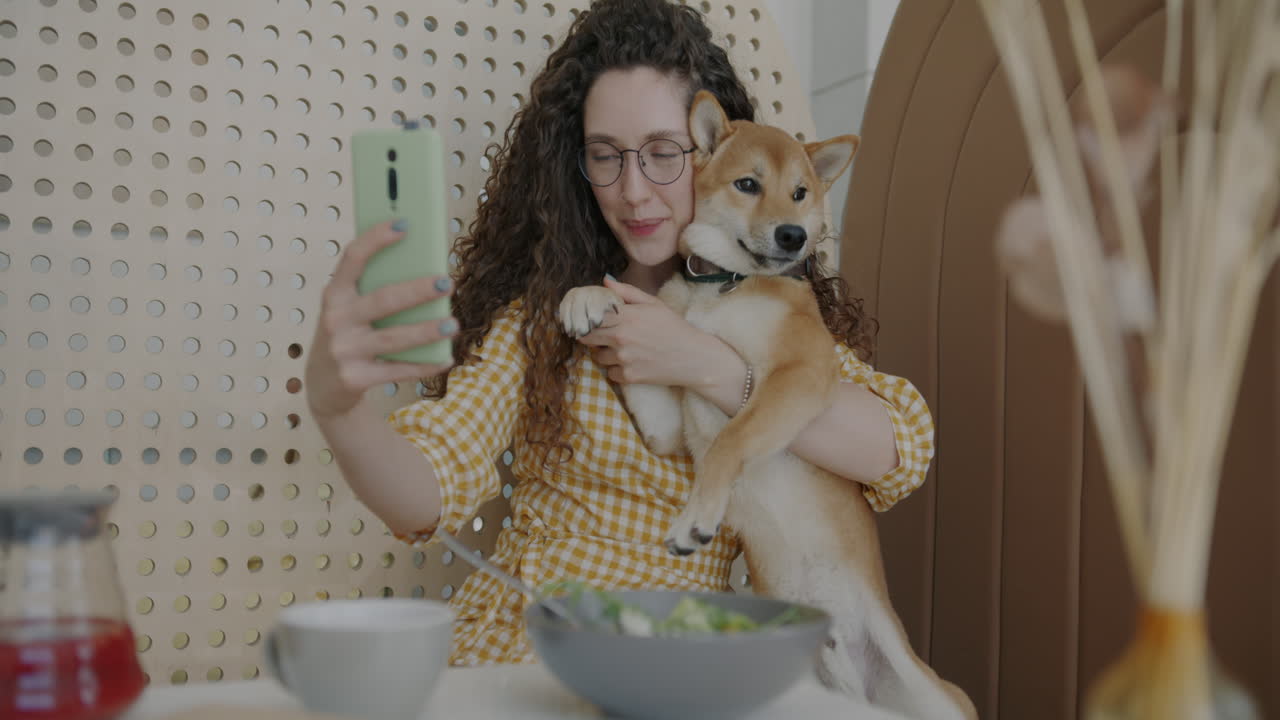 Woman taking a selfie with her Shiba Inu dog in a cafe