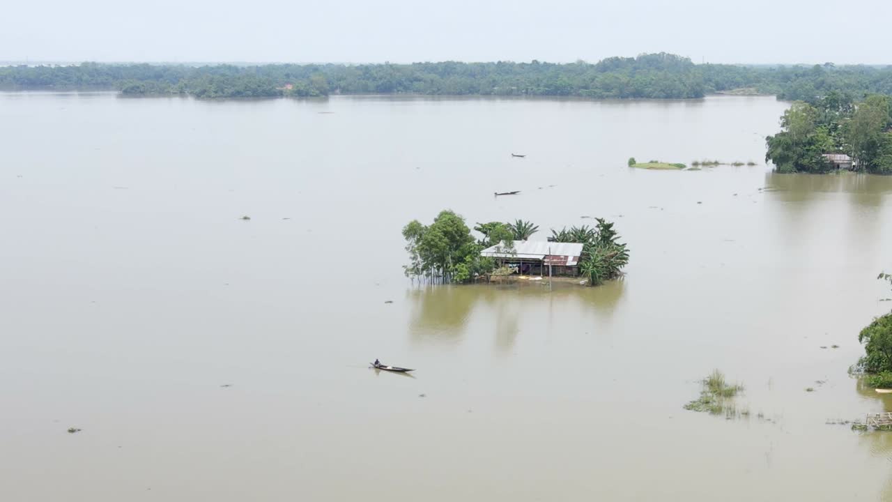 Flood damage showing submerged house with boat and surrounding village with forest in Bangladesh, South Asia - Sylhet