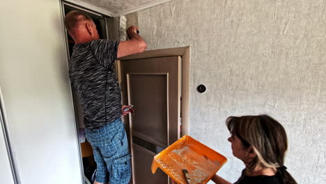 wife and husband doing room renovation with wallpaper together applying glue on wall
