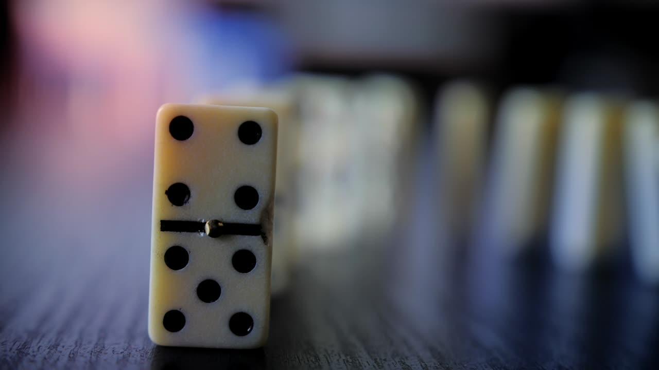 Dominobrikker falder i en kædereaktion på en mørk overflade
