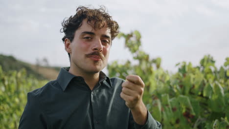 retrato de un hombre comiendo uvas en el viñedo. un viticultor comprobando la cosecha de la plantación.