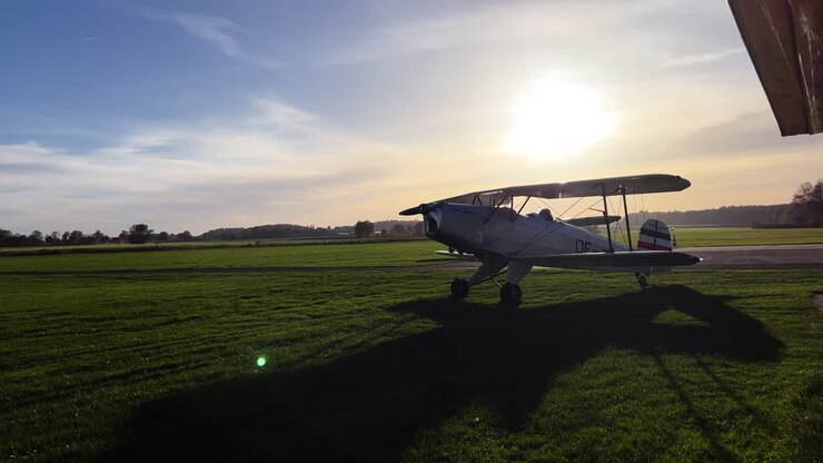 Mezzo campo lungo di un vecchio aereo d'epoca in fase di preparazione su una pista in erba.