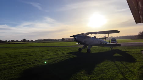 medium wide shot of an old vintage airplane standing on a grass rollway getting ready