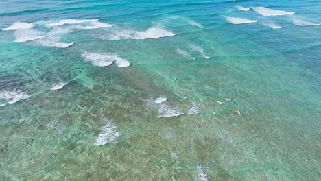 birdseye shot of surfers on waves on oahu, hawaii, bright blue turquoise water with white caps