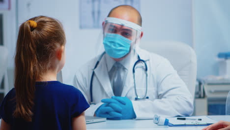 un médico amistoso hablando con un pequeño paciente.