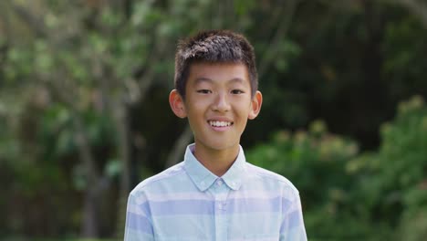 Portrait-of-happy-asian-boy-looking-to-camera-smiling-and-laughing-in-garden