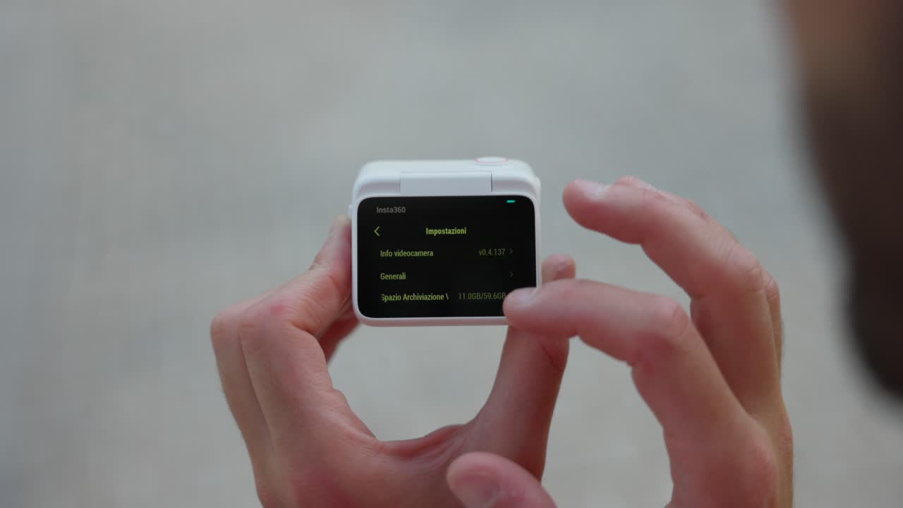 freelancer sosteniendo la cápsula de acción insta360 go 3 y desplazándose por la pantalla lcd posterior
