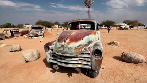 Viejos-Y-Oxidados-Restos-De-Autos-Antiguos-En-Exhibición-En-La-Remota-Parada-Agrícola-De-Solitaire-En-Namibia