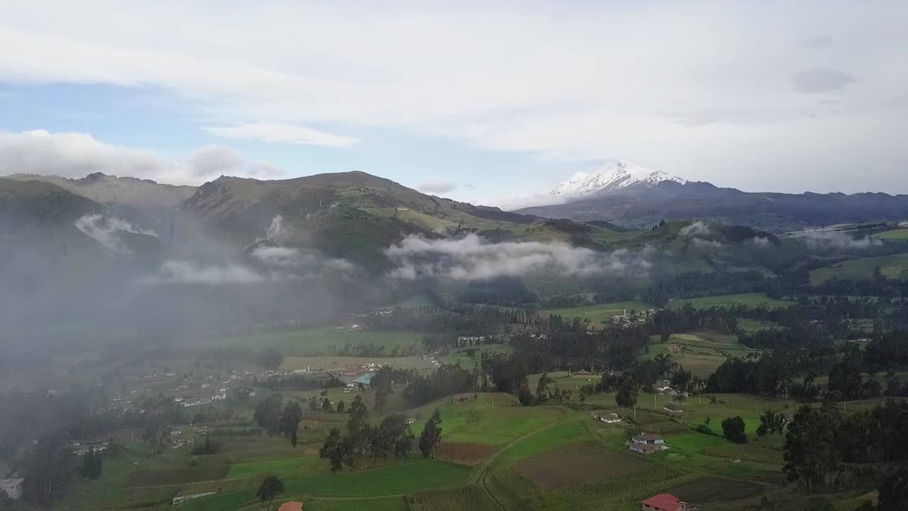 Foggy and cloudy valley landscape with small houses in aerial drone view
