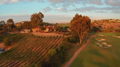 Orangefarbener-Sonnenuntergang-Auf-Einem-Hügeligen-Golfplatz,-Clubhaus,-Landschaftsansicht