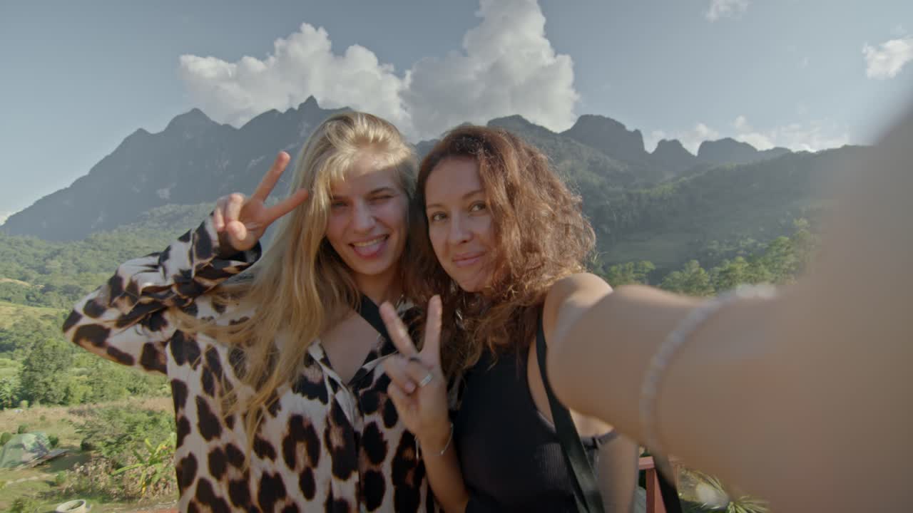 Two friends taking a selfie in front of mountains