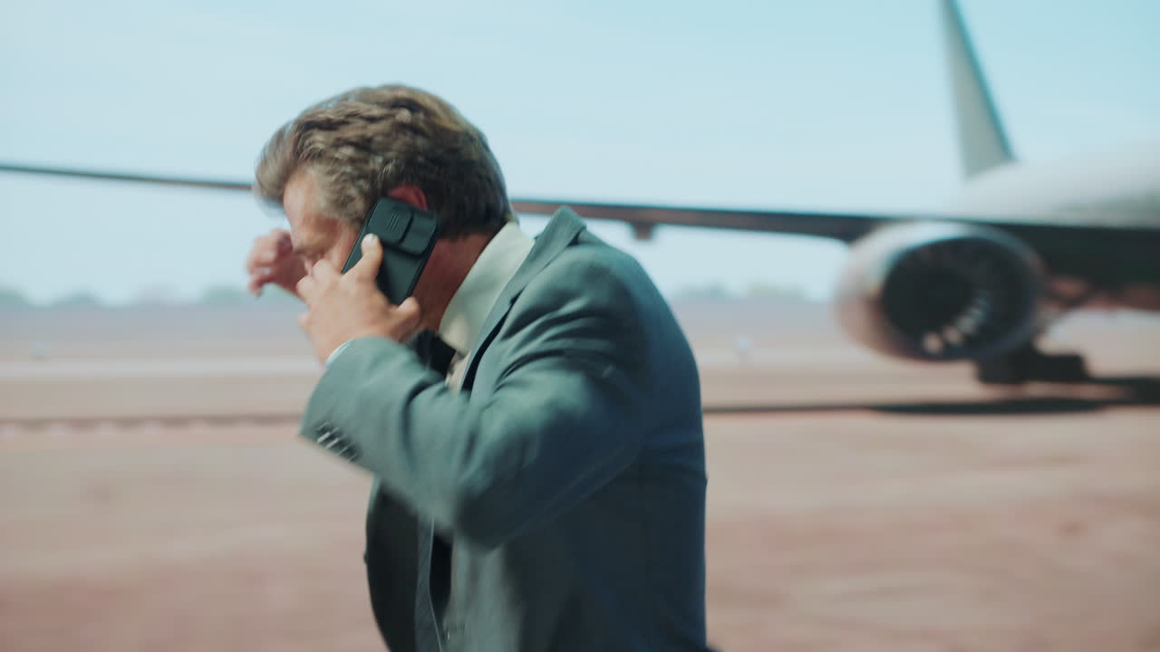 Man in suit on phone near airplane